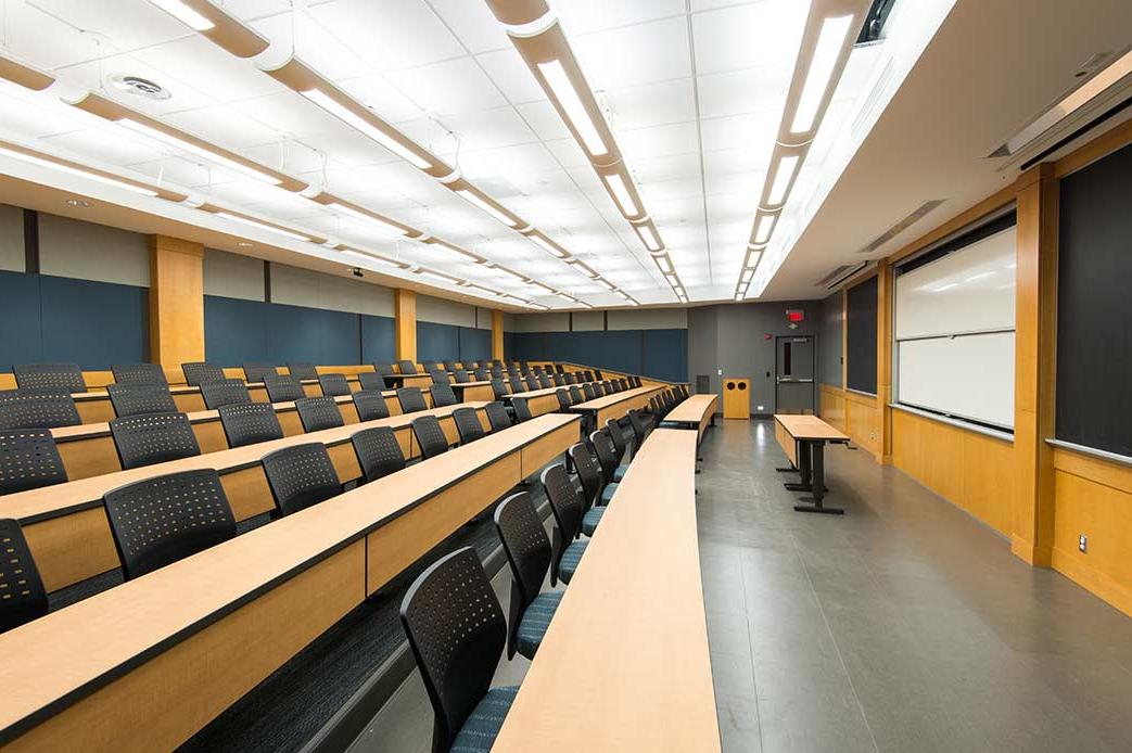 large, empty classroom shows seats, desks, screen.