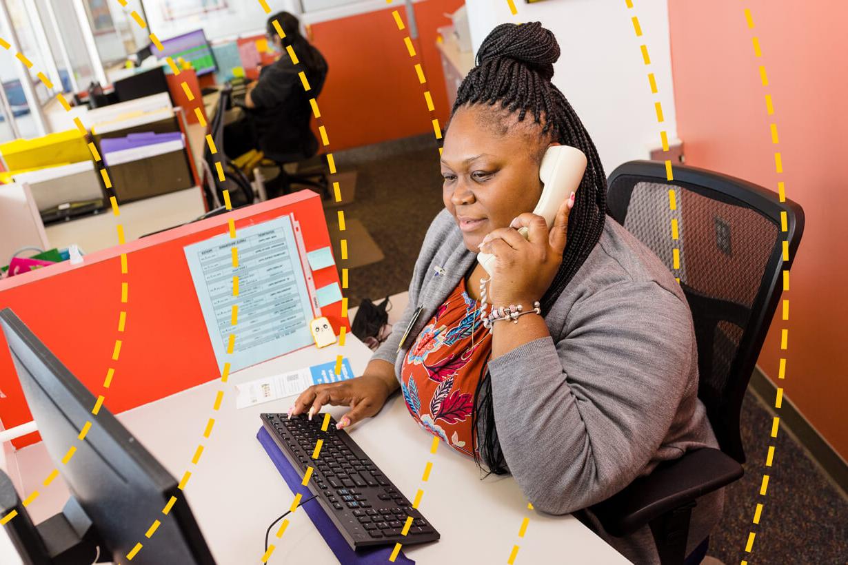University of Rochester staff memeber answers a phone while seated at a desk.